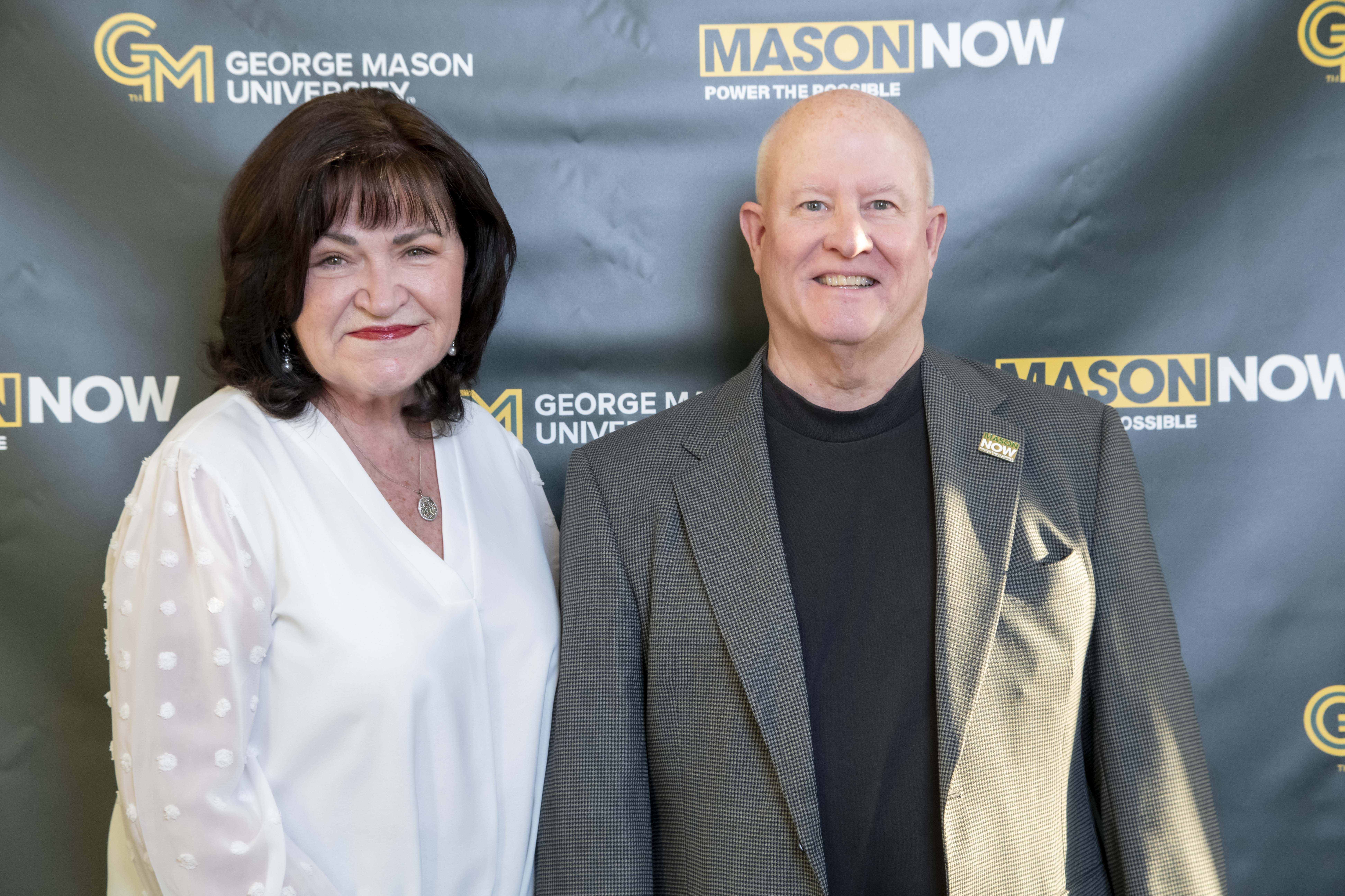 Two 2024 Winter Celebration of Giving reception attendees with Mason Now backdrop.