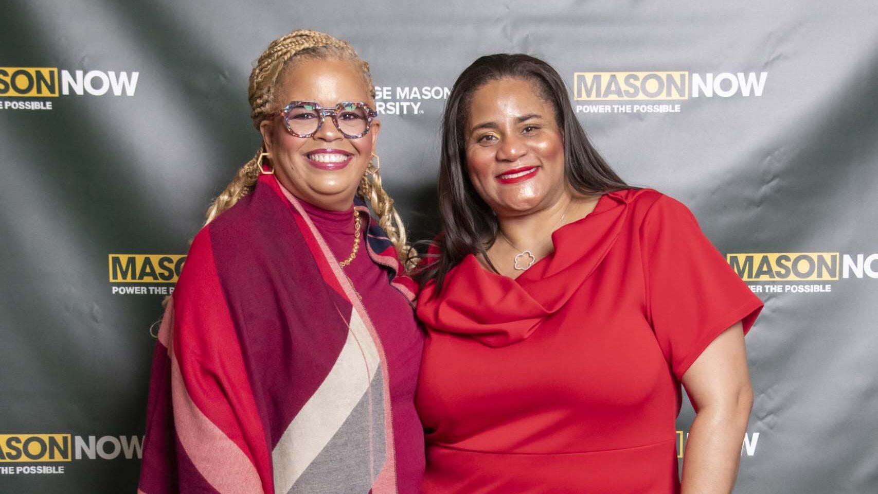 Two 2024 Winter Celebration of Giving reception attendees with Mason Now backdrop.