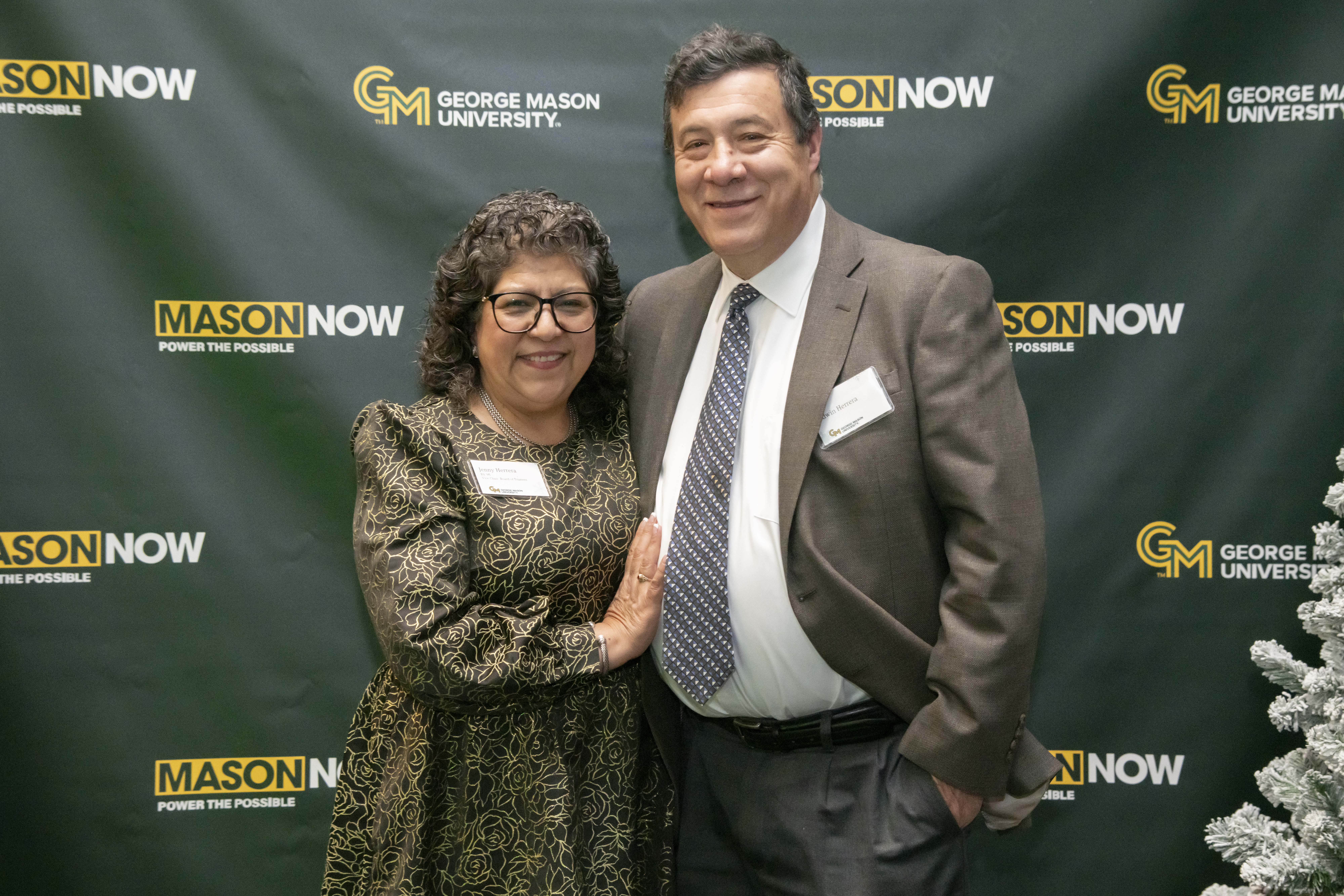 Two 2024 Winter Celebration of Giving reception attendees with Mason Now backdrop.