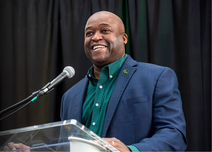 The president of George Mason smiling and giving a speech at a podium