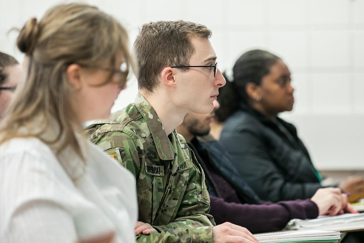 Three students seated with one wearing a military uniform