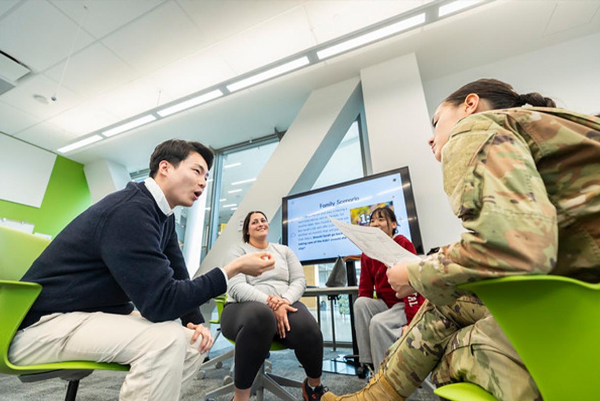 Students talking with each other in a green and metal conference room