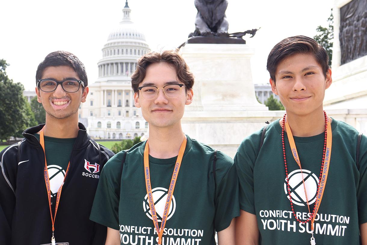 Three young students wearing Conflict Resolution Summit t-shirts and medals