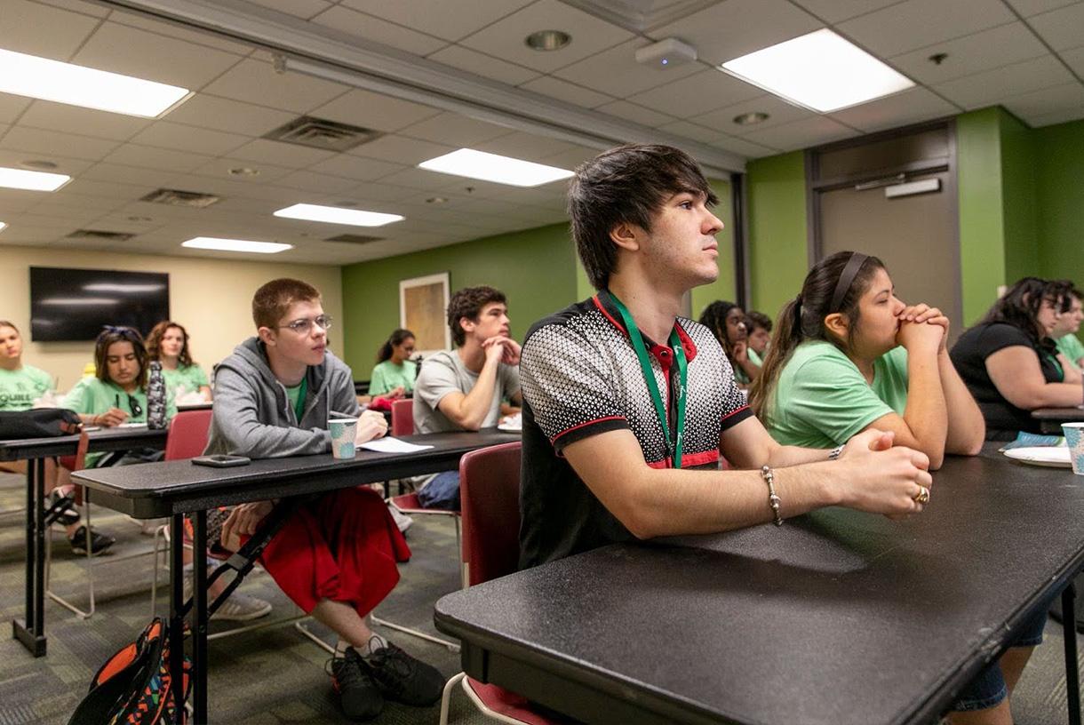 Students sitting at desks and listening to speaker