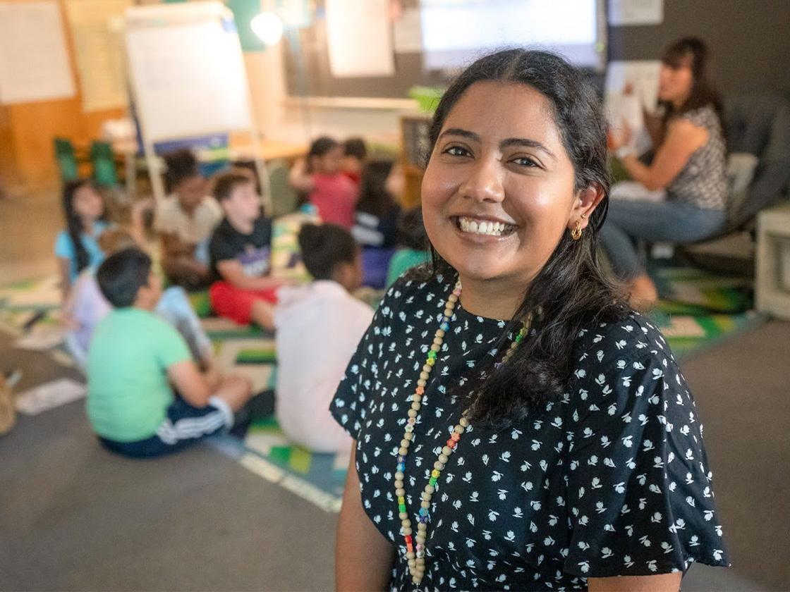 Teacher smiling with kids seated behind her