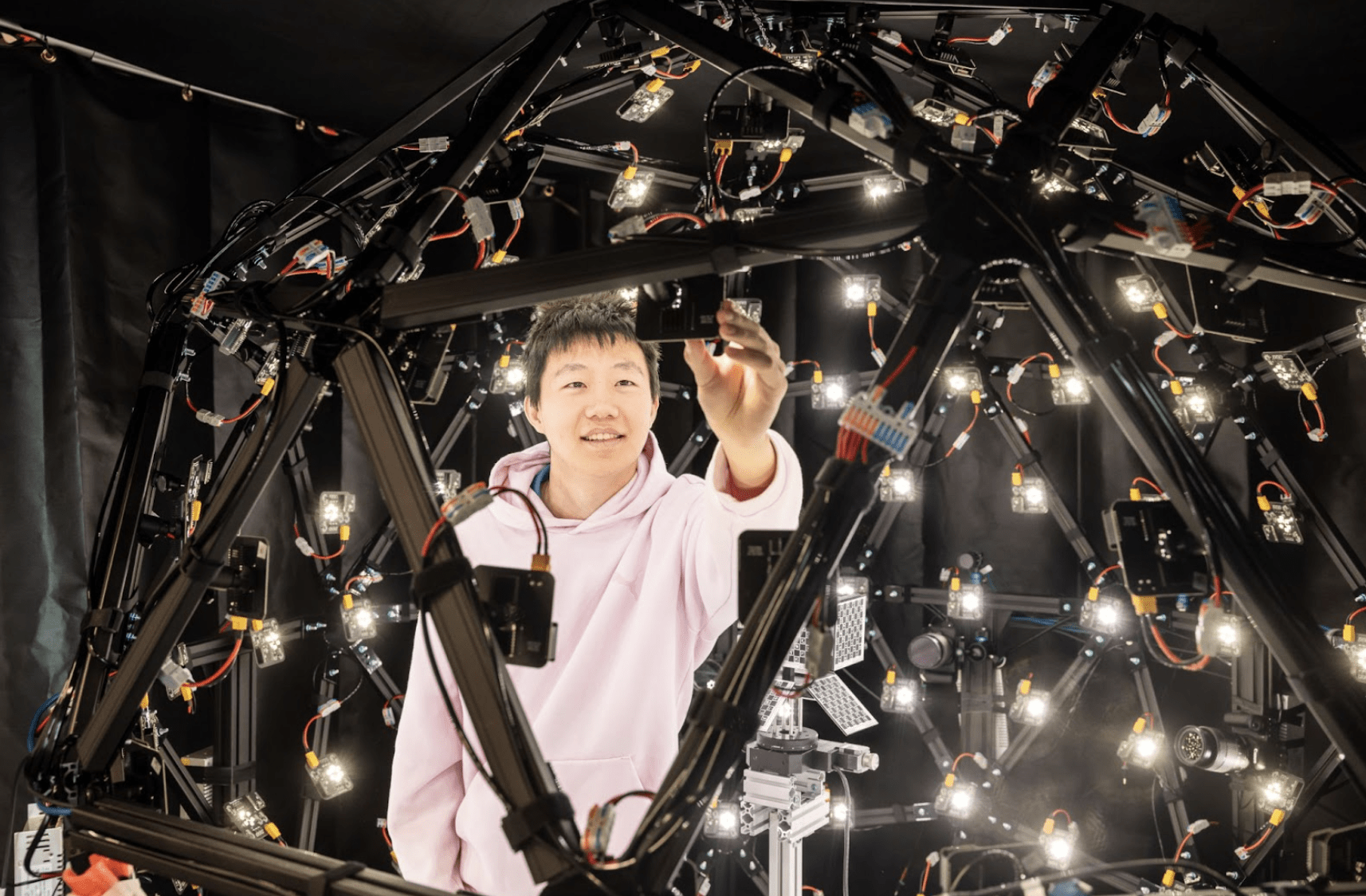 Smiling student inside a robotic hemispheric device with lights