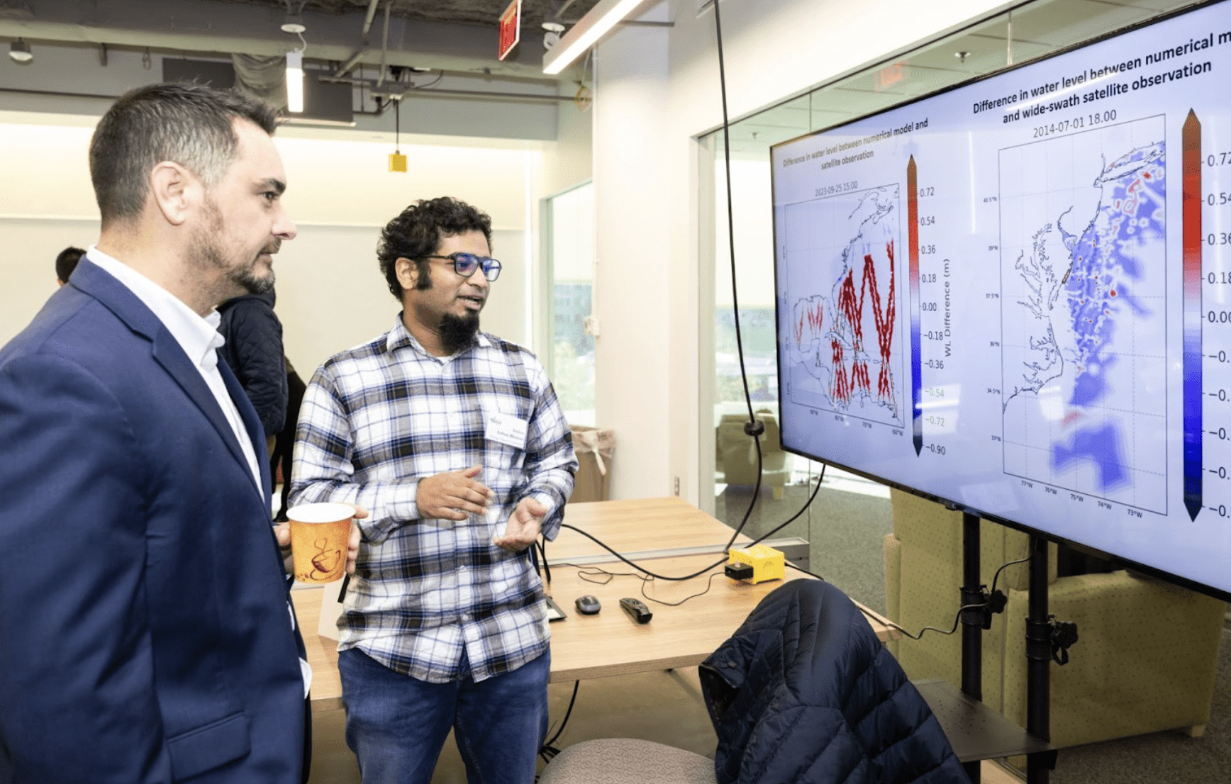 Faculty and student looking at bar graphs on large digital screen