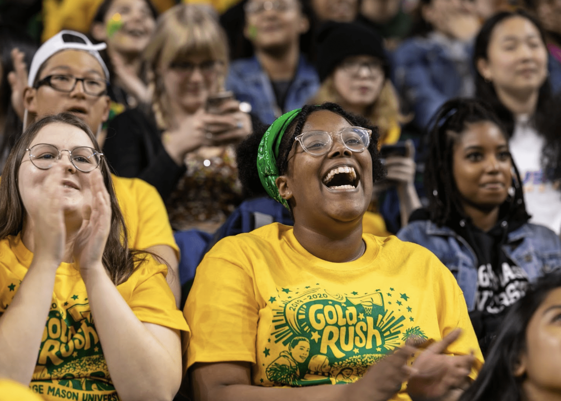 Smiling student wearing bright yellow shirt in an audience
