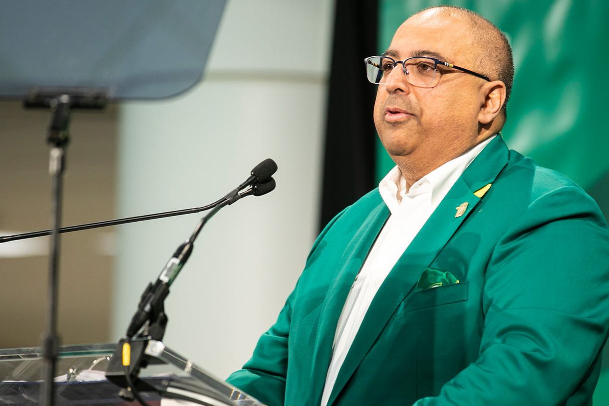Man wearing green blazer speaking at podium