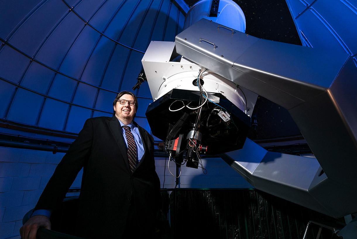 Smiling man posing with large space machinery