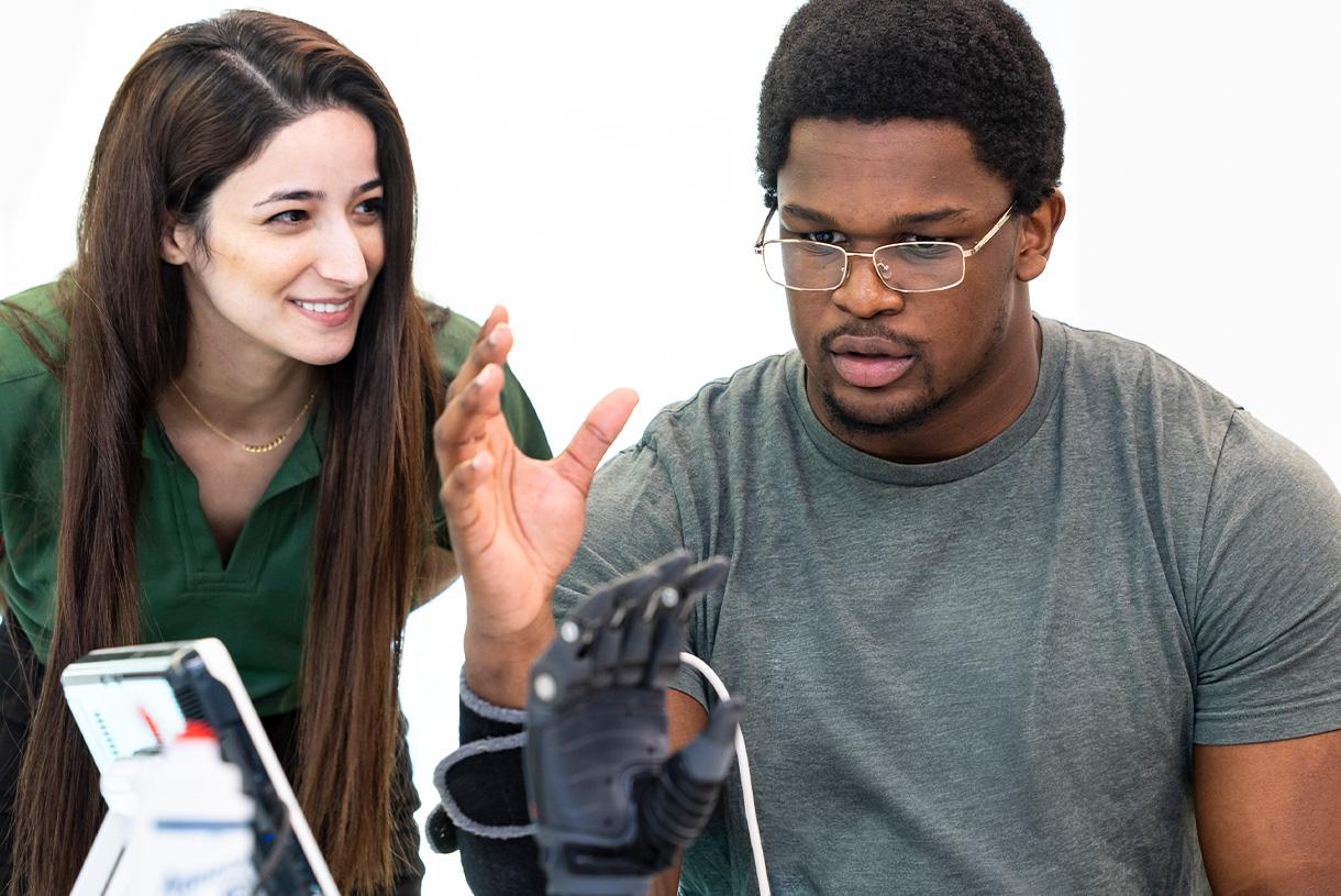 A man testing a hand robot with another woman standing beside him