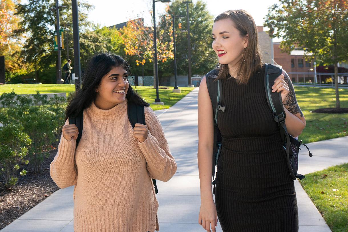 Two smiling students walking together outside