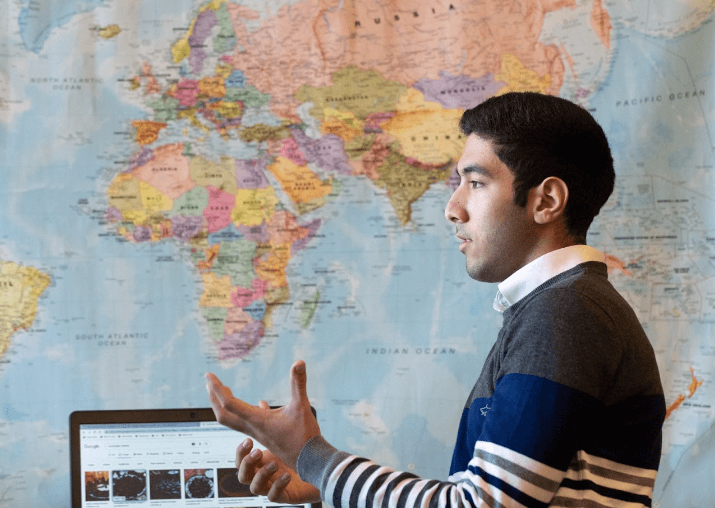 Man speaking with world map behind him