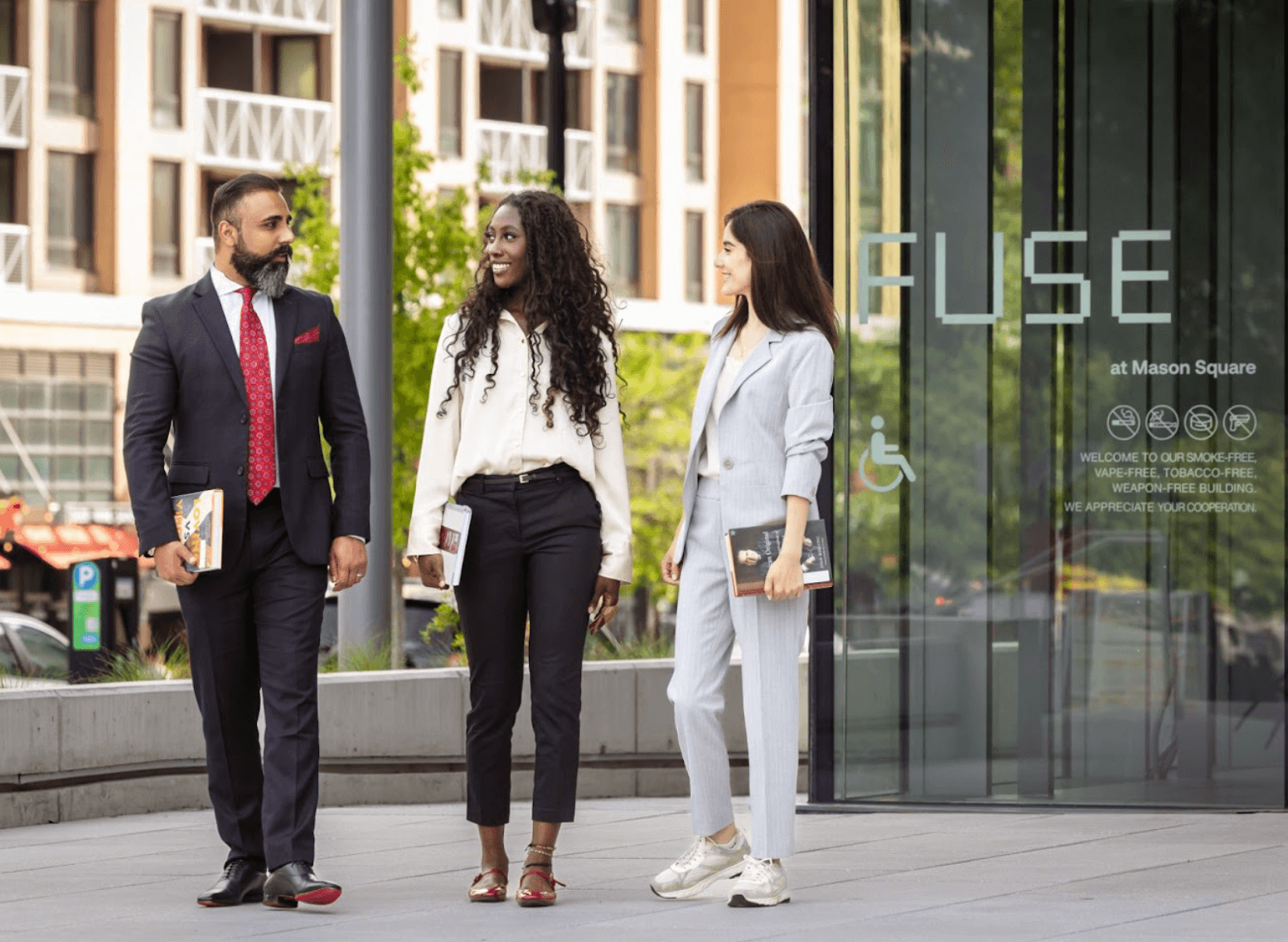 Three people wearing business attire standing outside the FUSE building
