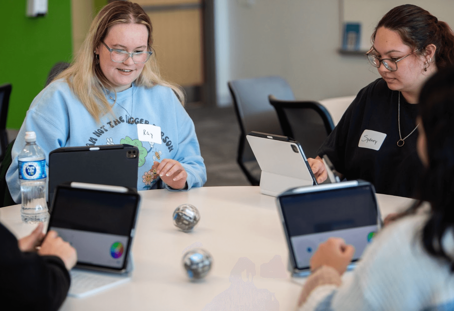 Four students sitting at a round table with laptops