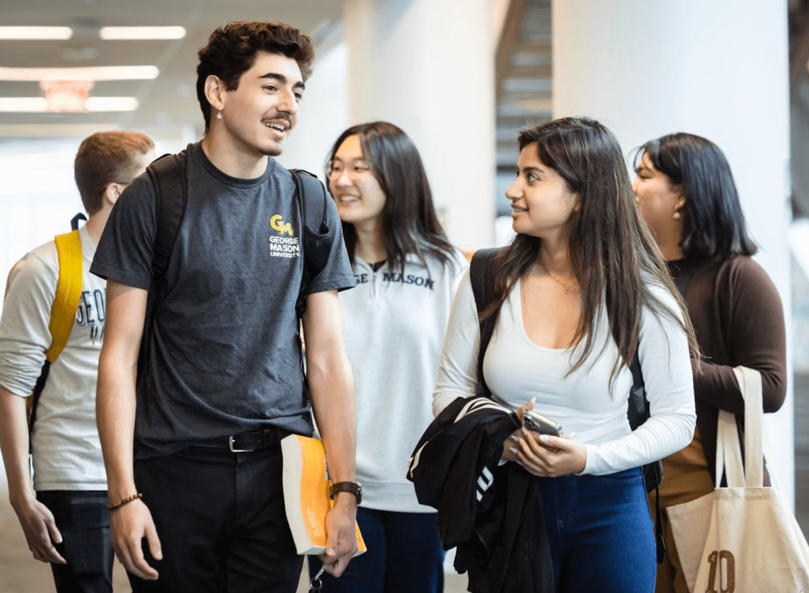A group of smiling students walking down the hall together