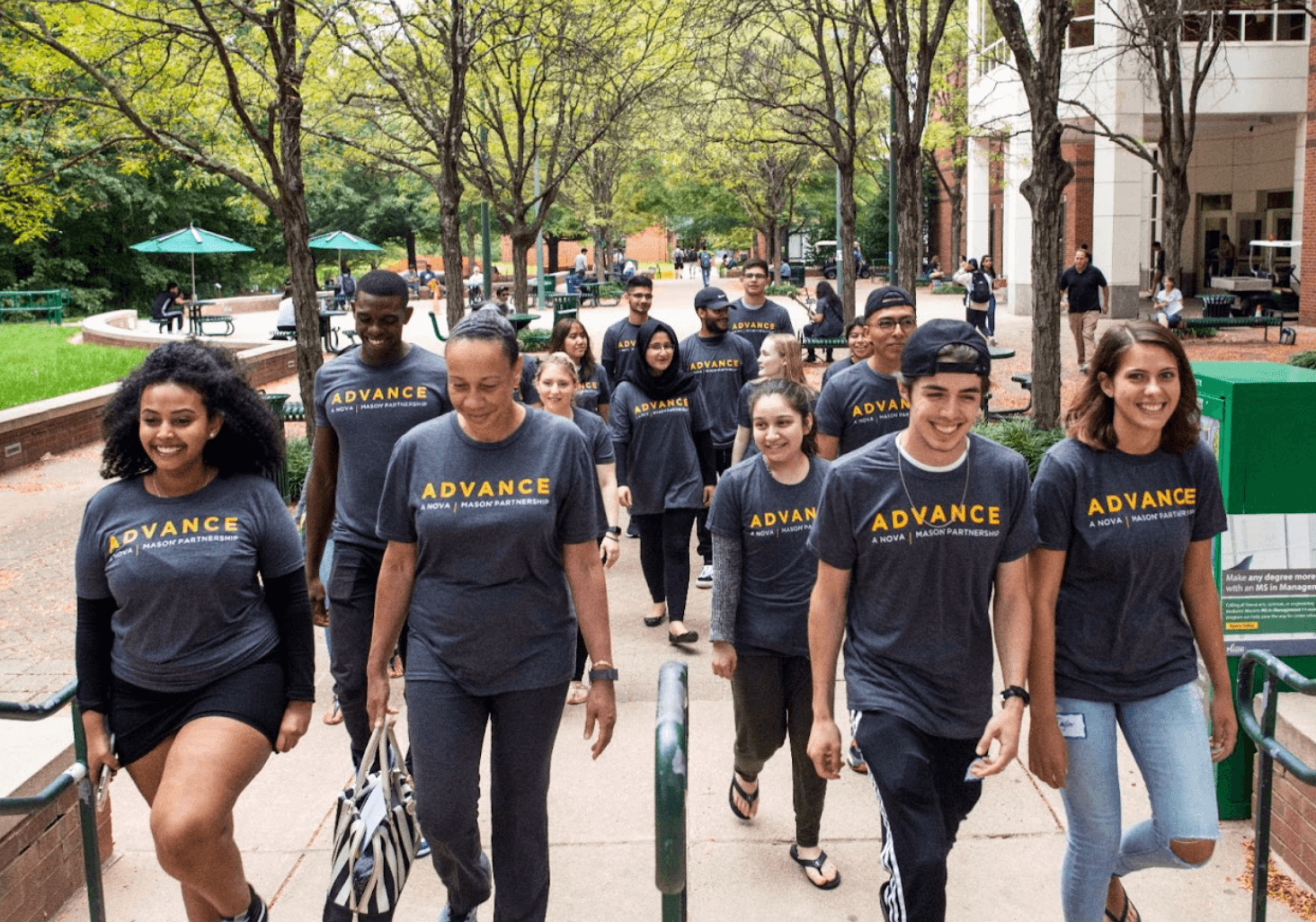 A group of students walking outside and wearing matching grey Advance t-shirts
