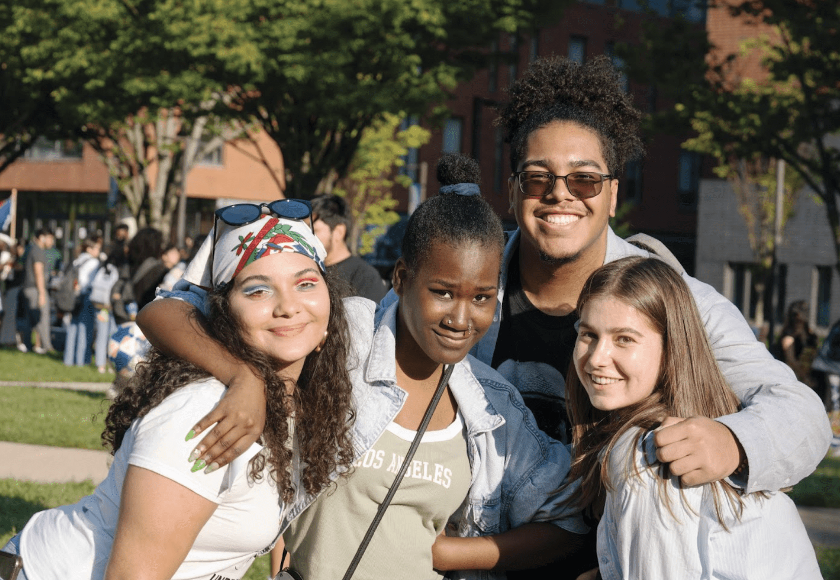 Four smiling students outside and hugging