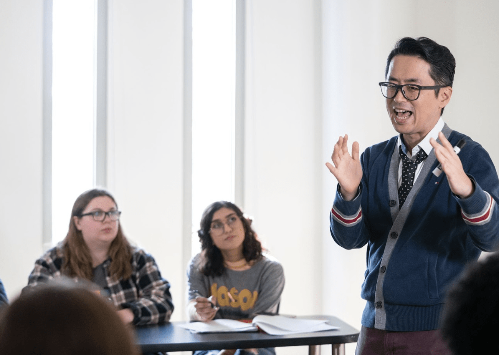 A faculty speaking during a lecture with two students in background