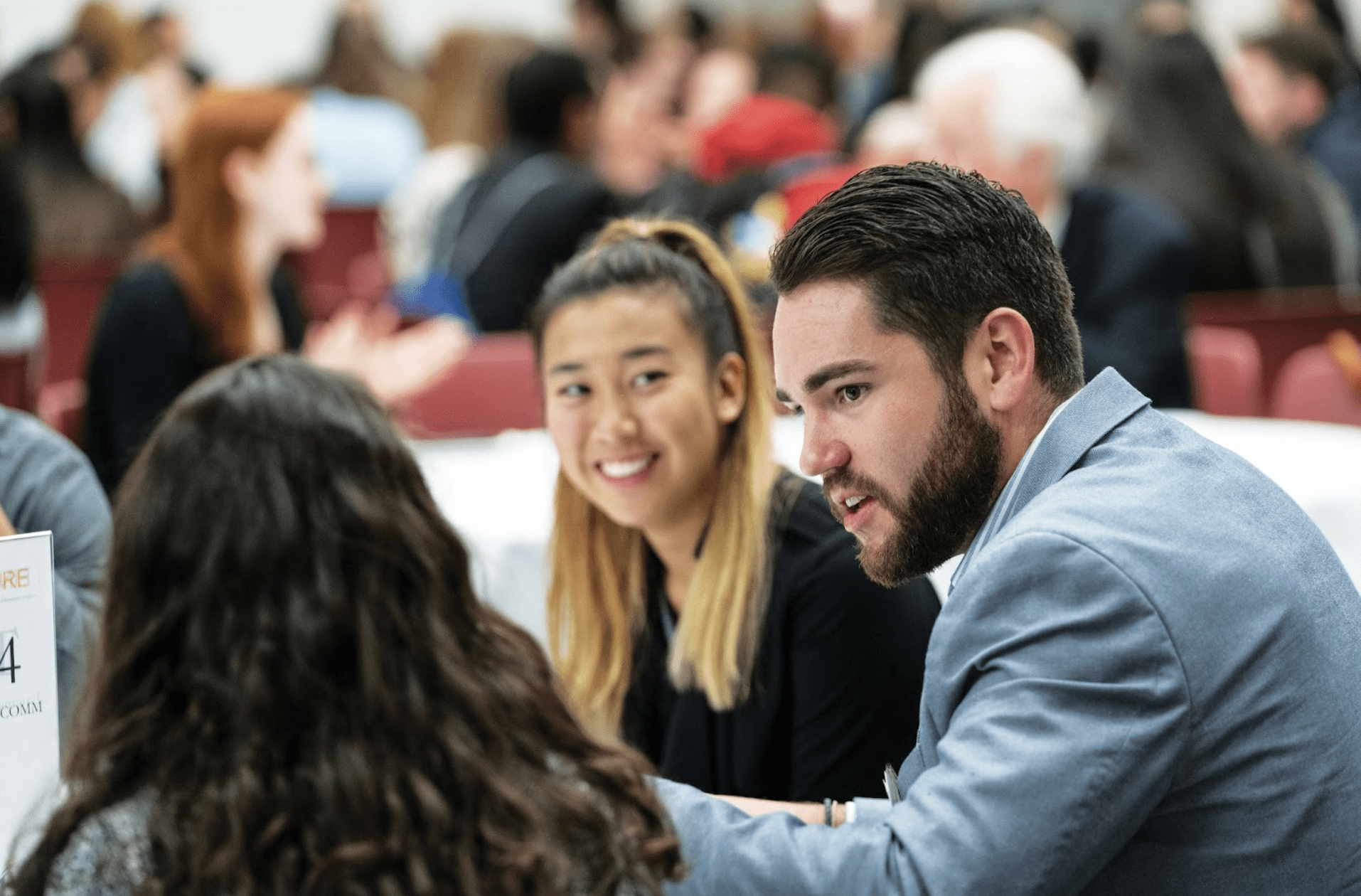 A smiling student sitting next to another student in a hall