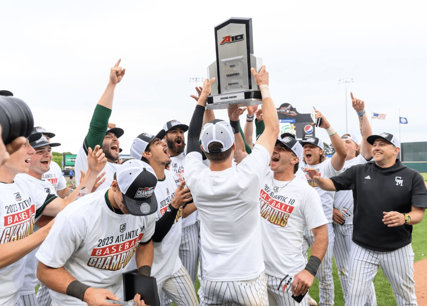 Baseball team members cheering and holding a trophy