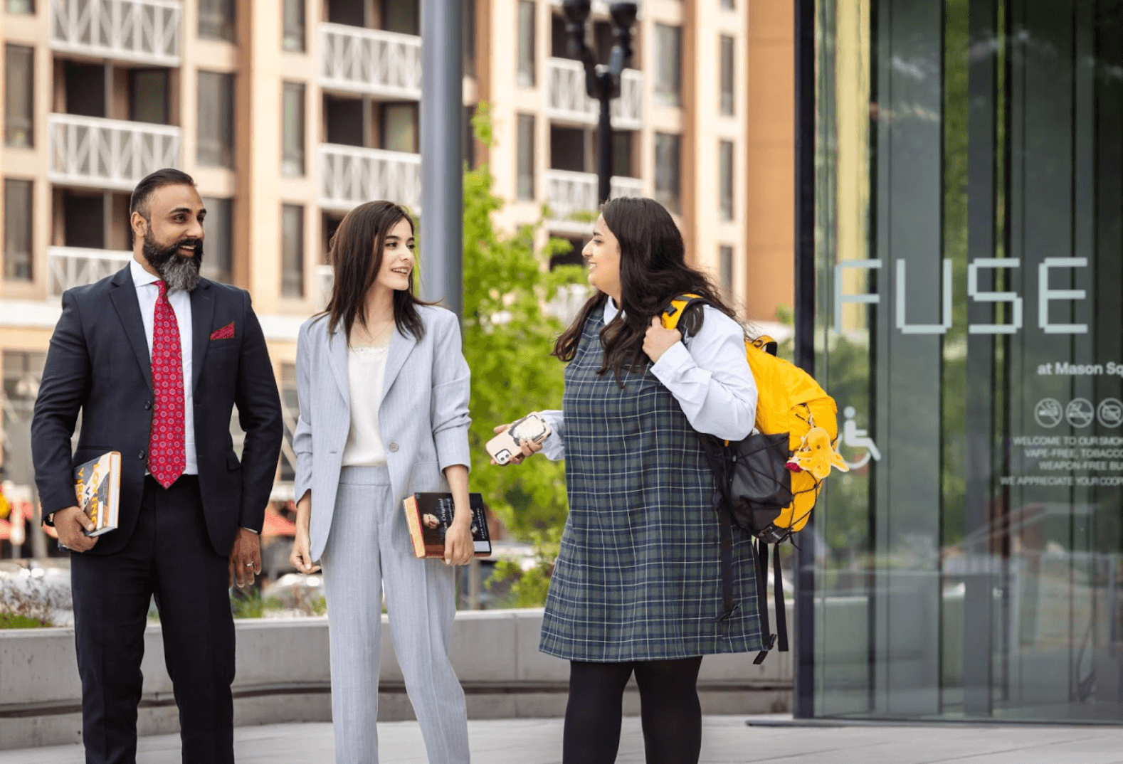 Three people in business attire and standing in front of the FUSE building