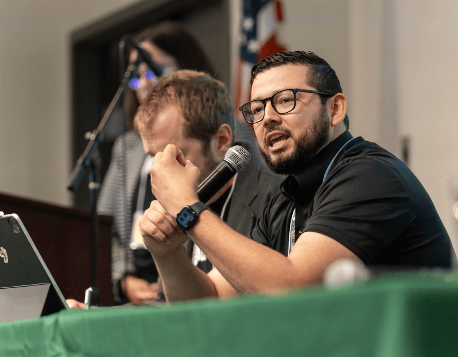 Student speaking into a microphone and sitting at a green table