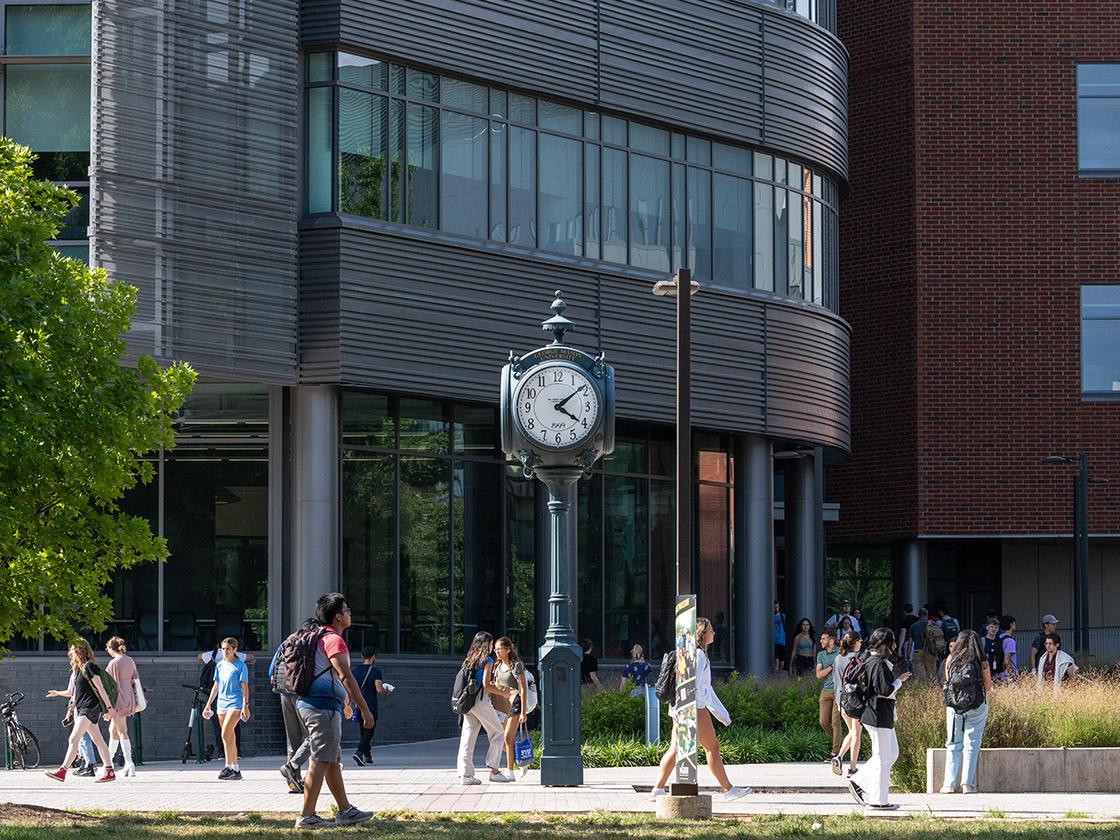 Distant photo of students walking in front of a clock tower