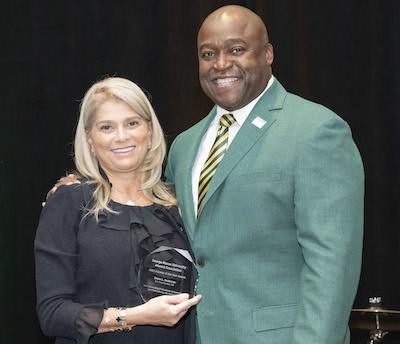Alumna of the Year Shaza L. Andersen stands beside President Washington while holding an award.