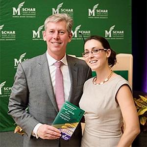 Colin Hart stands beside Marisol Maddox in front of a green background featuring the George Mason logo.