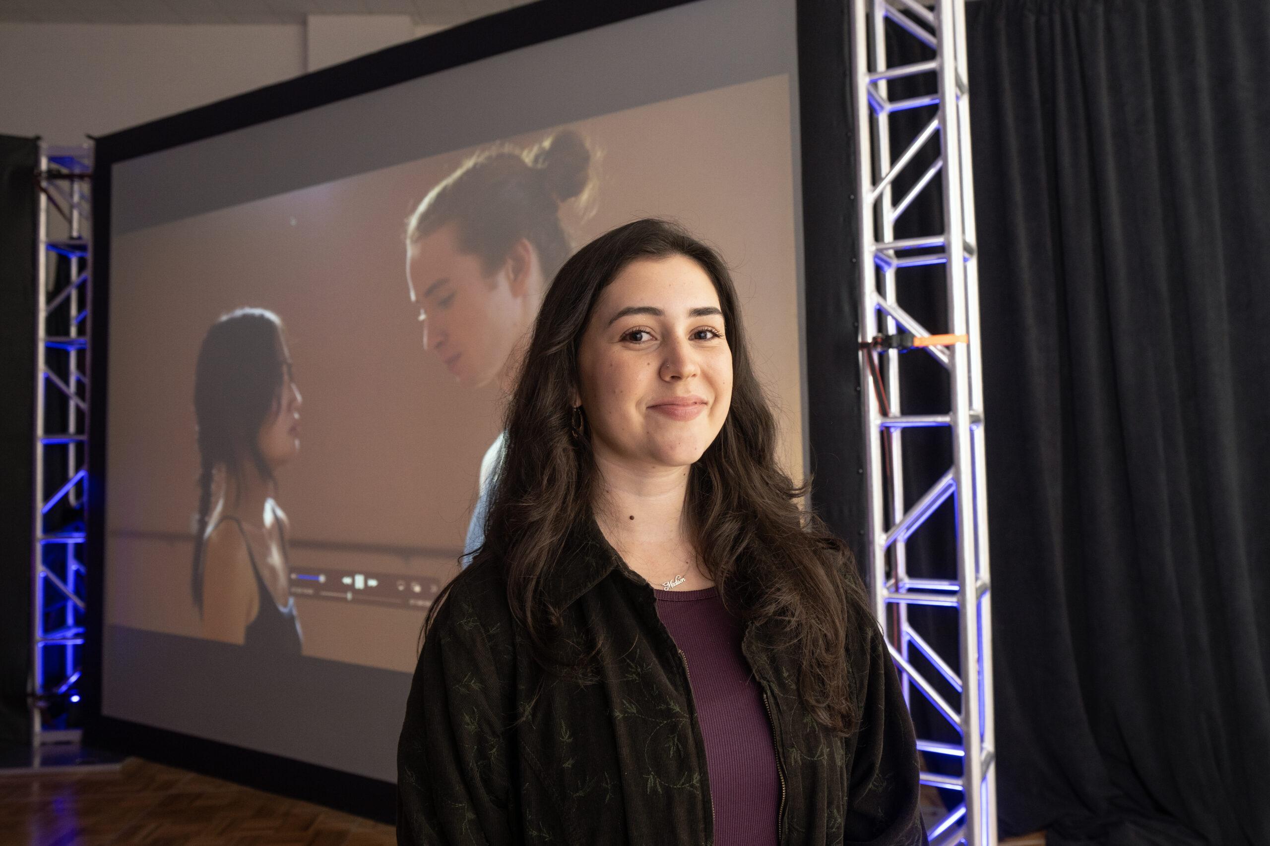 Student stands in front of a projector.