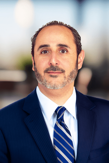Ali Reza Manouchehri in a navy blue suit and tie