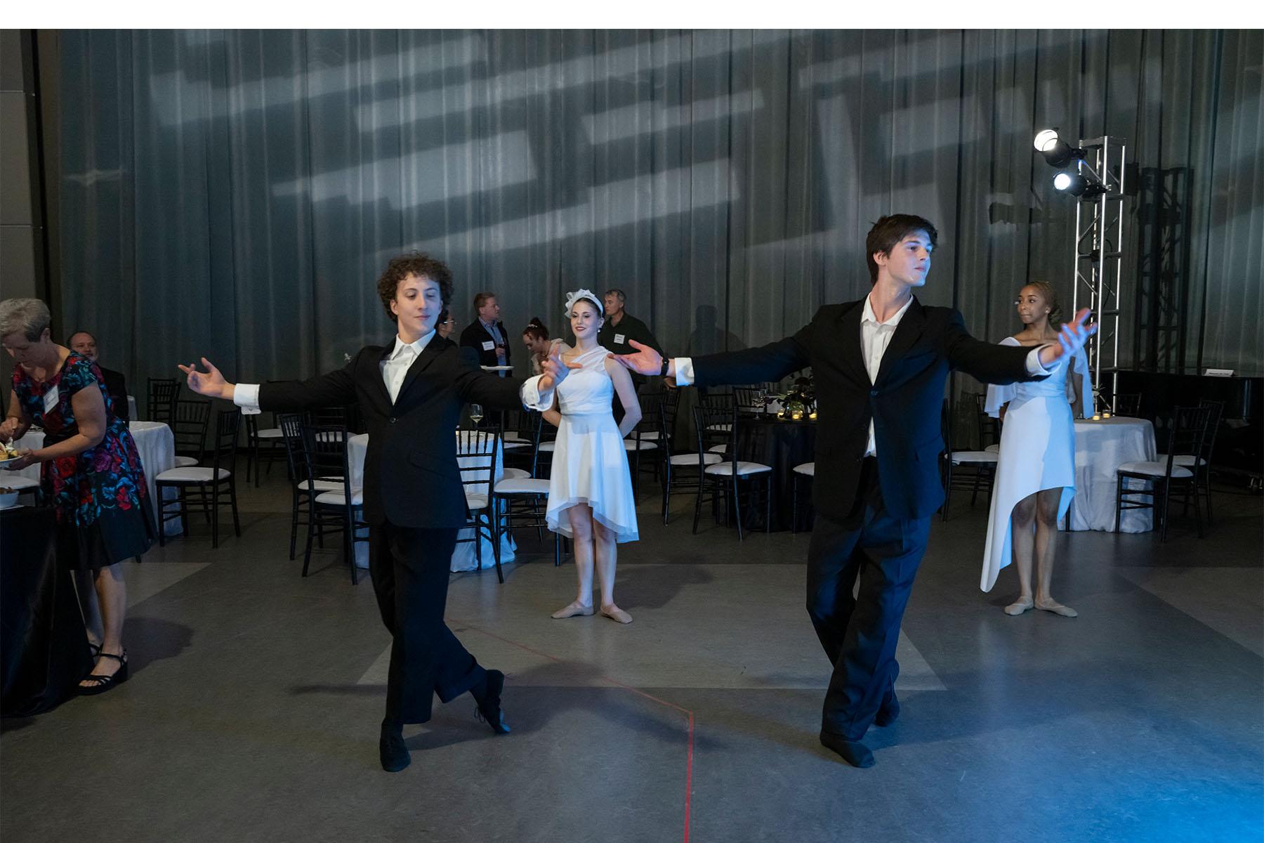 Four dancers perform together in a reception space.