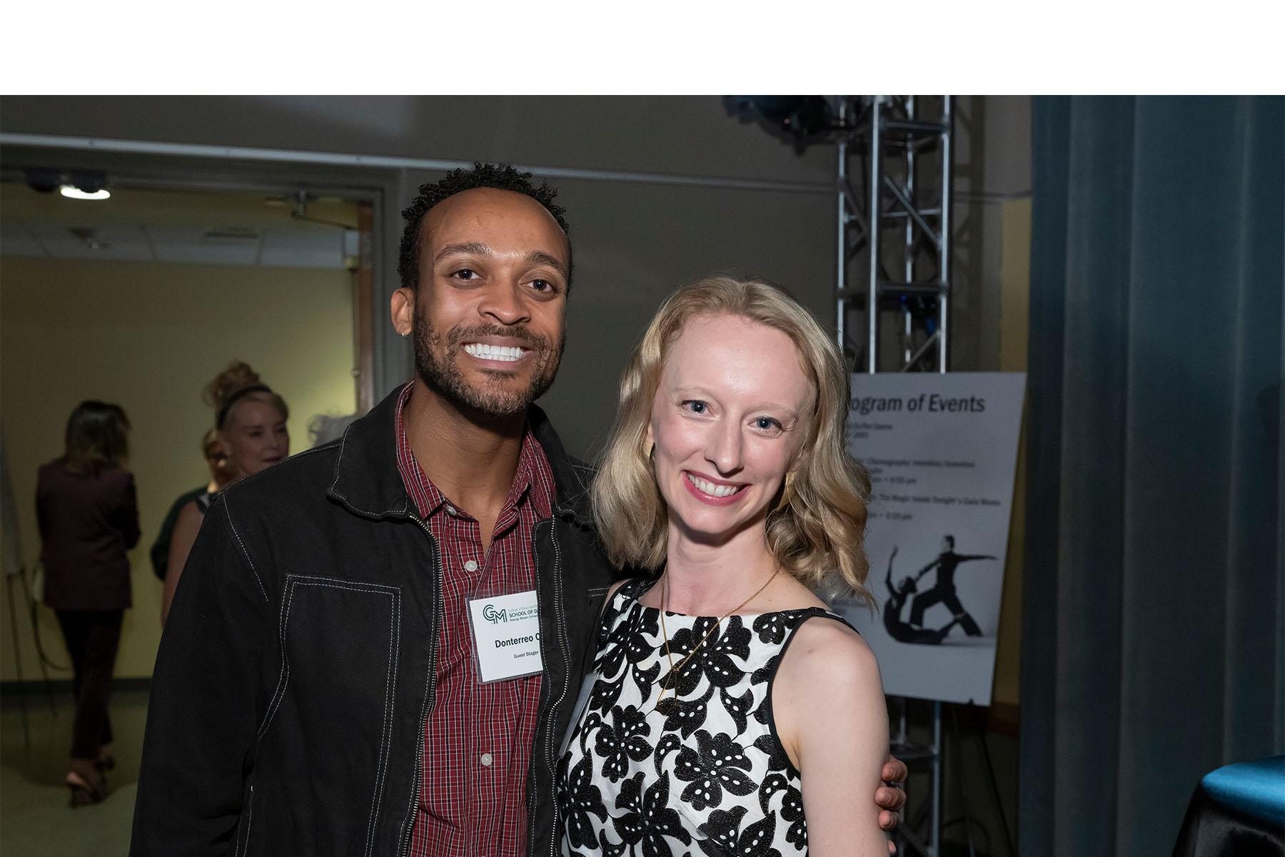 Two event attendees stand together.