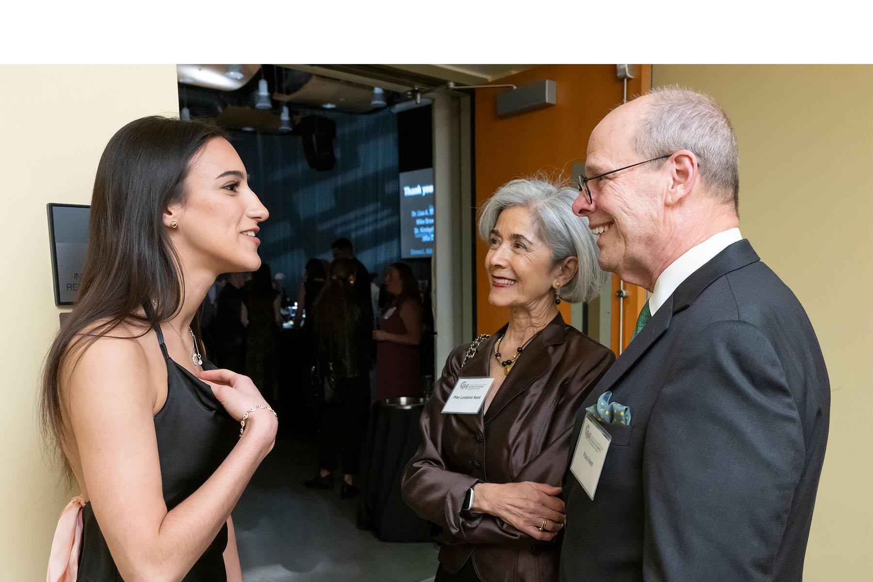 Two event attendees speaking with a dancer.