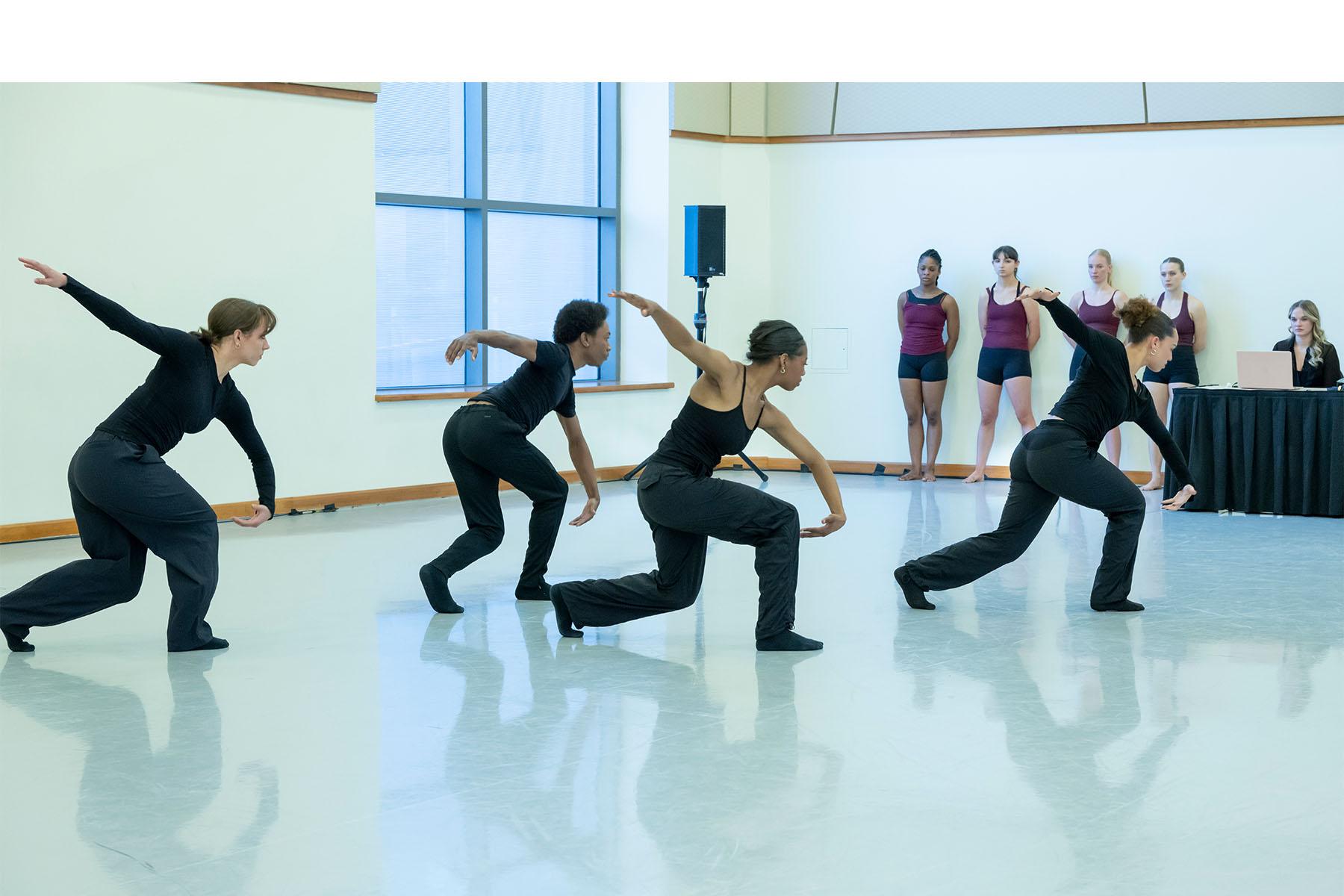 Four dancers perform in a dance studio.