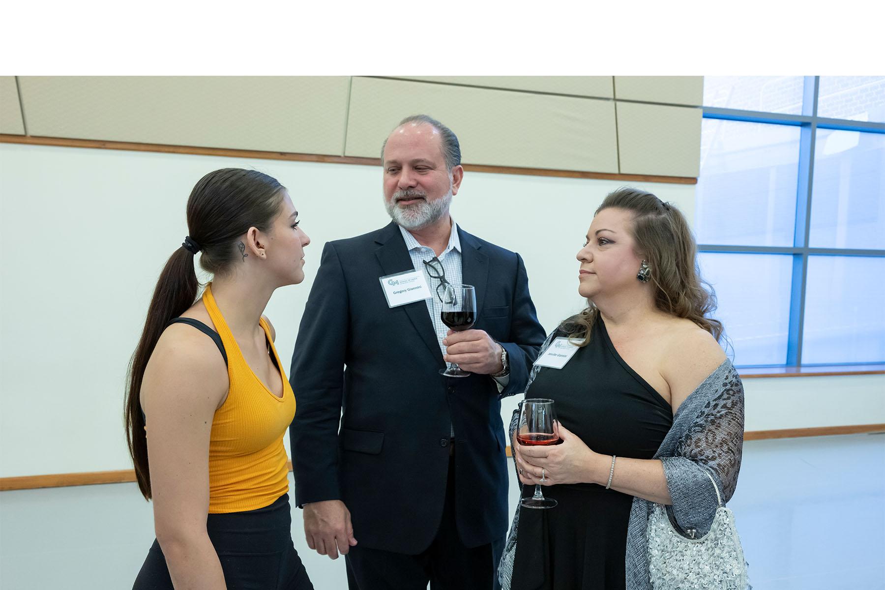 Two event attendees speaking with a dancer.