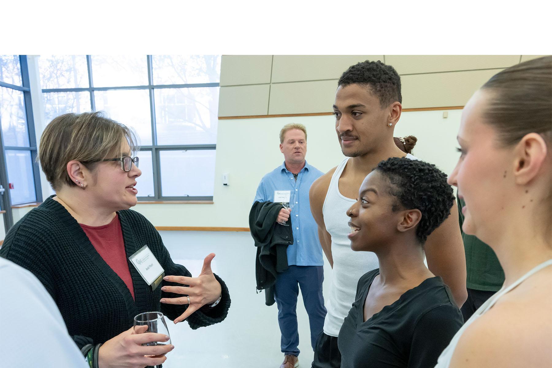 An event attendee speaking with three dancers.
