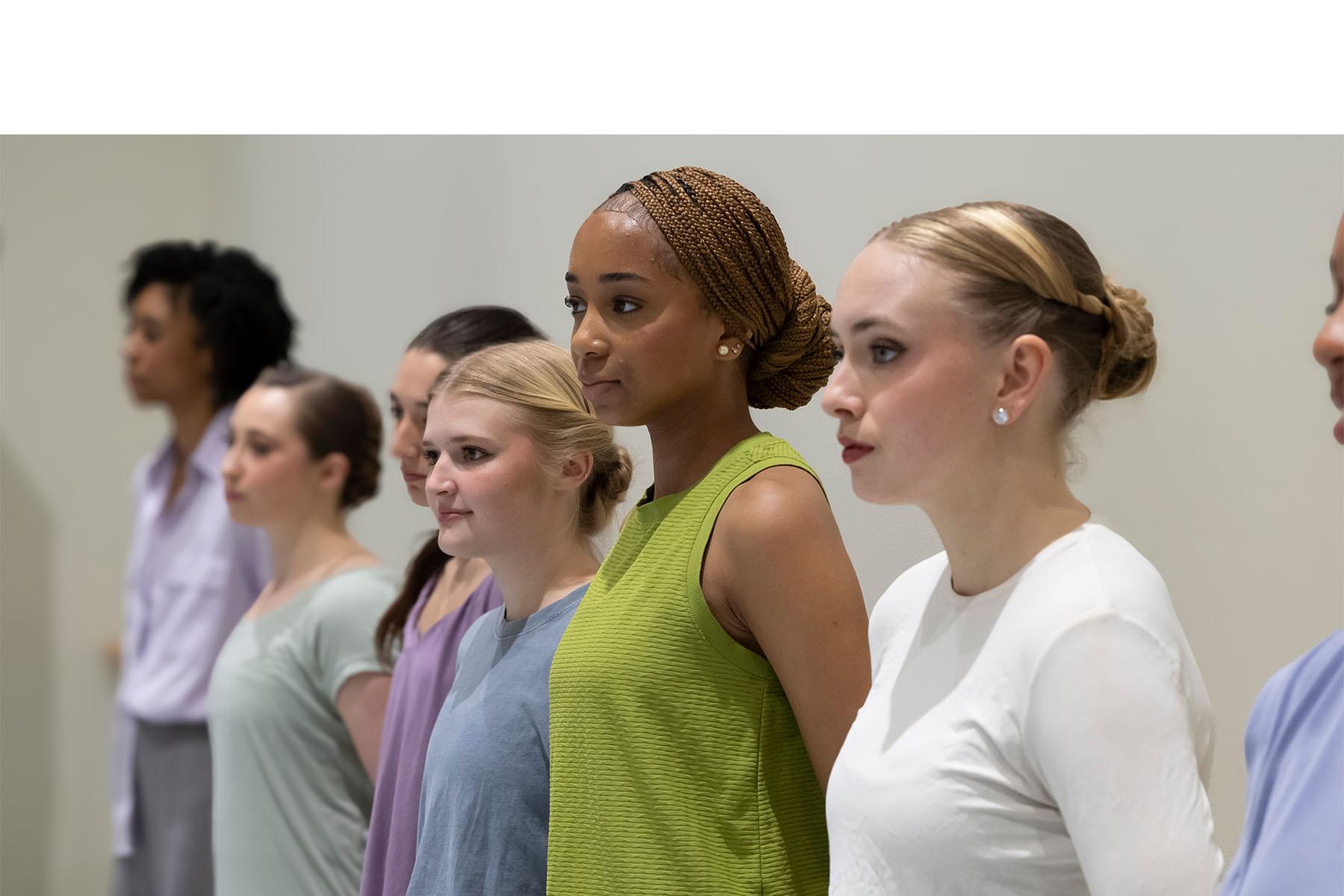 Five dancers standing together in a dance studio.
