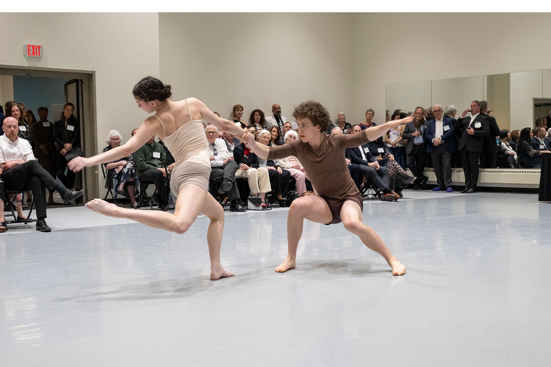 Two dancers perform in a dance studio.