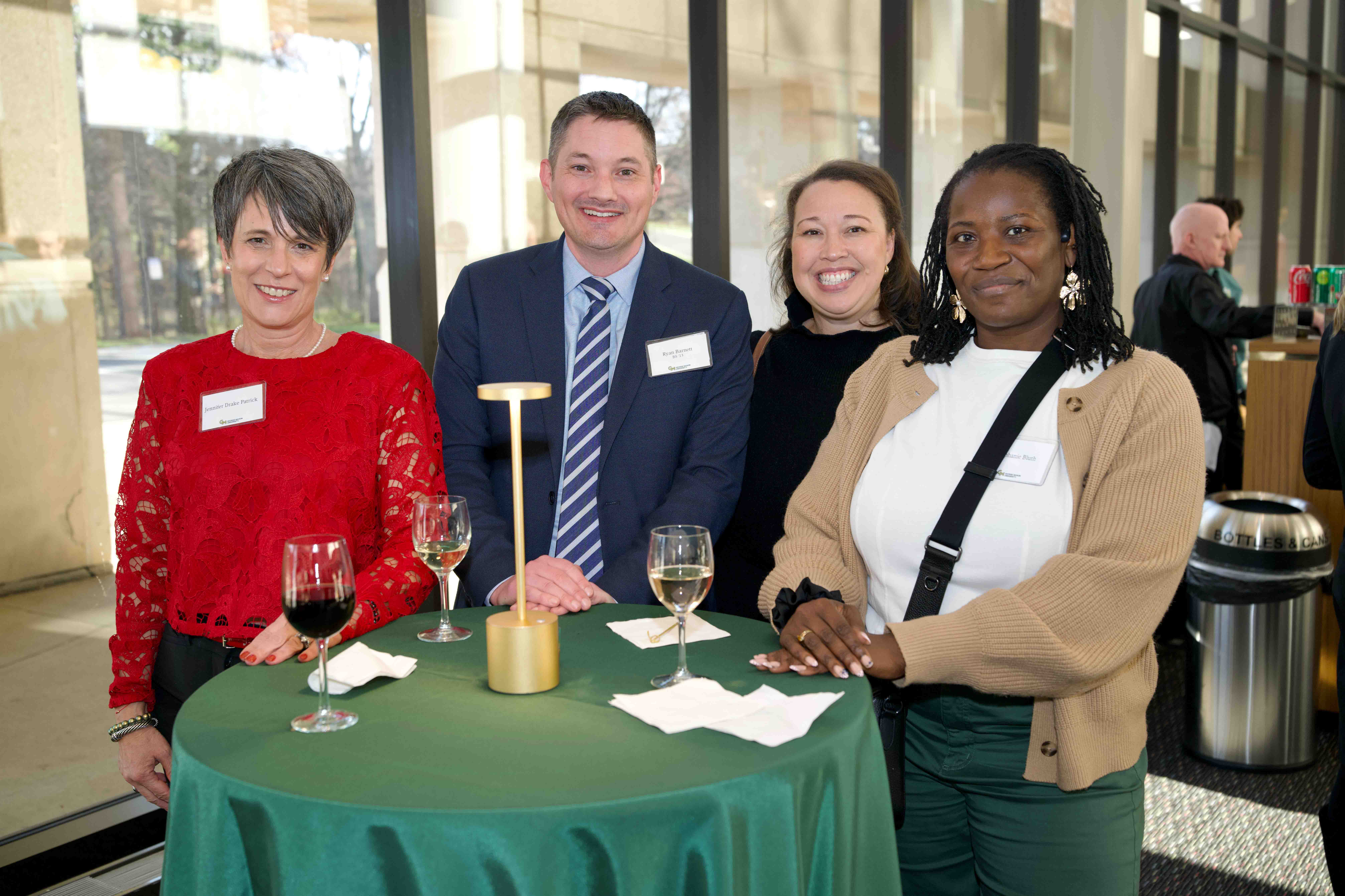 Four attendees stand together around a table at Celebrating Our Champions event.