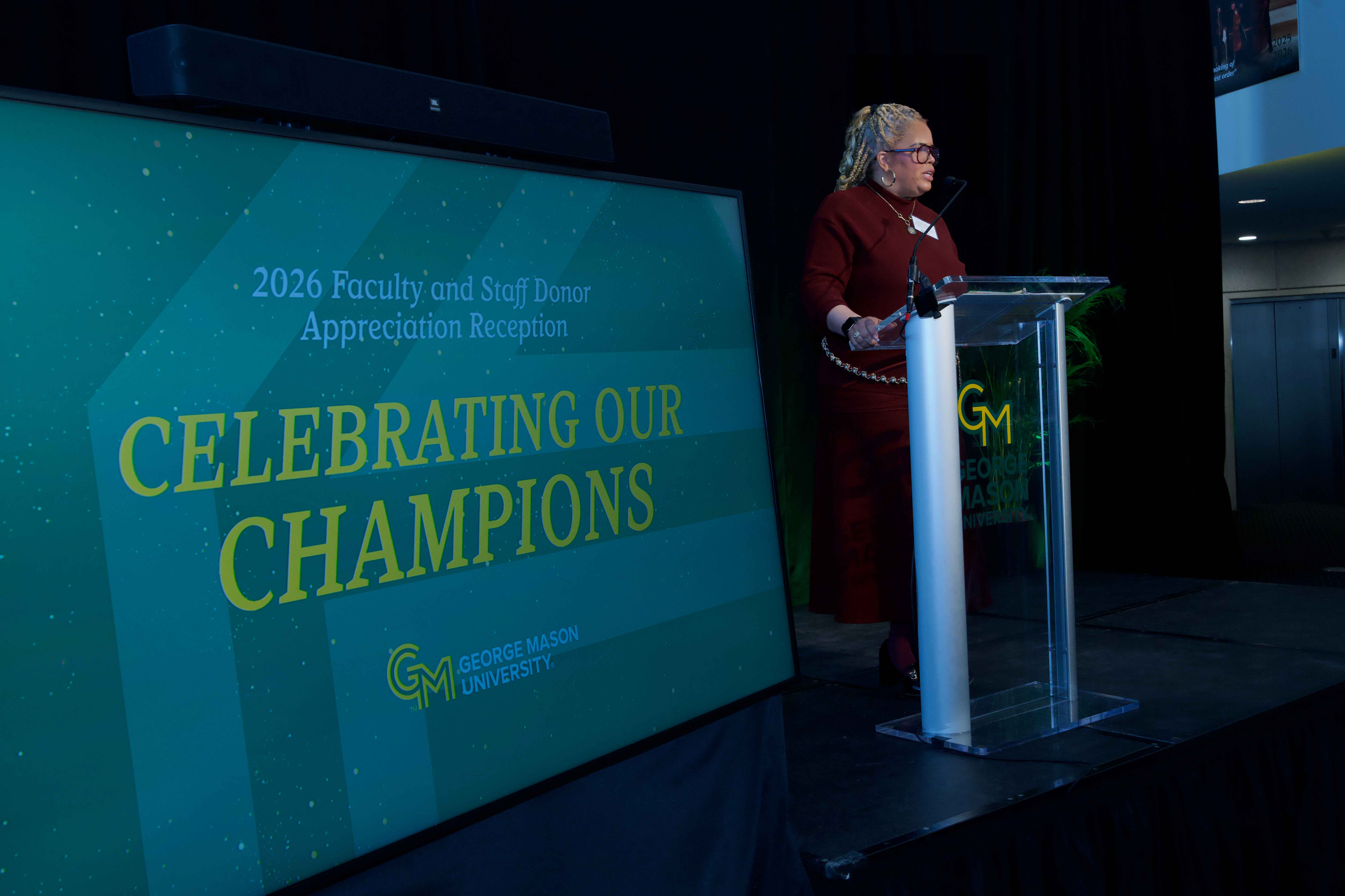 Trishana Bowden stands at podium at Celebrating Our Champions event.