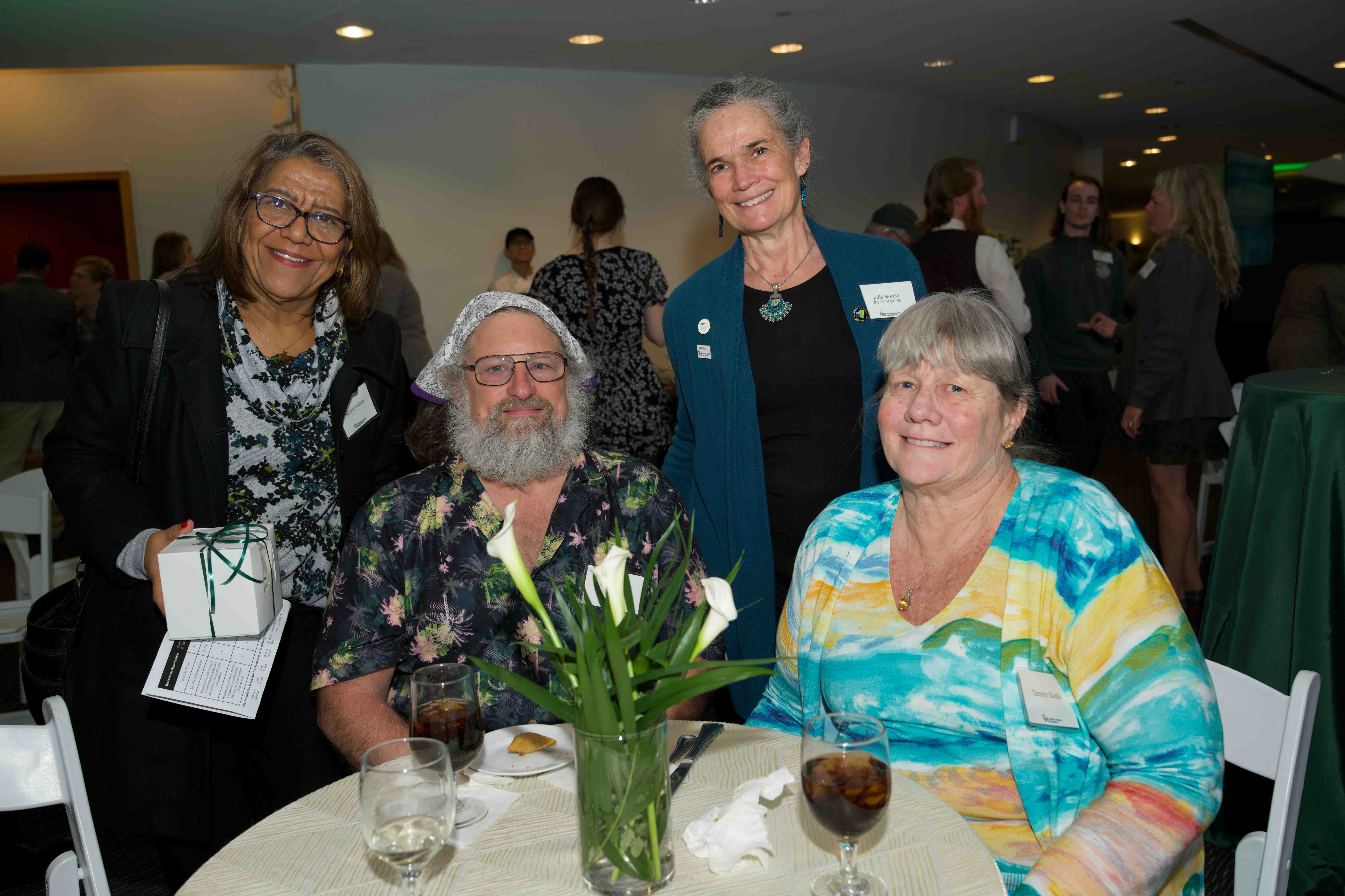 Four attendees stand together around a table at Celebrating Our Champions event.