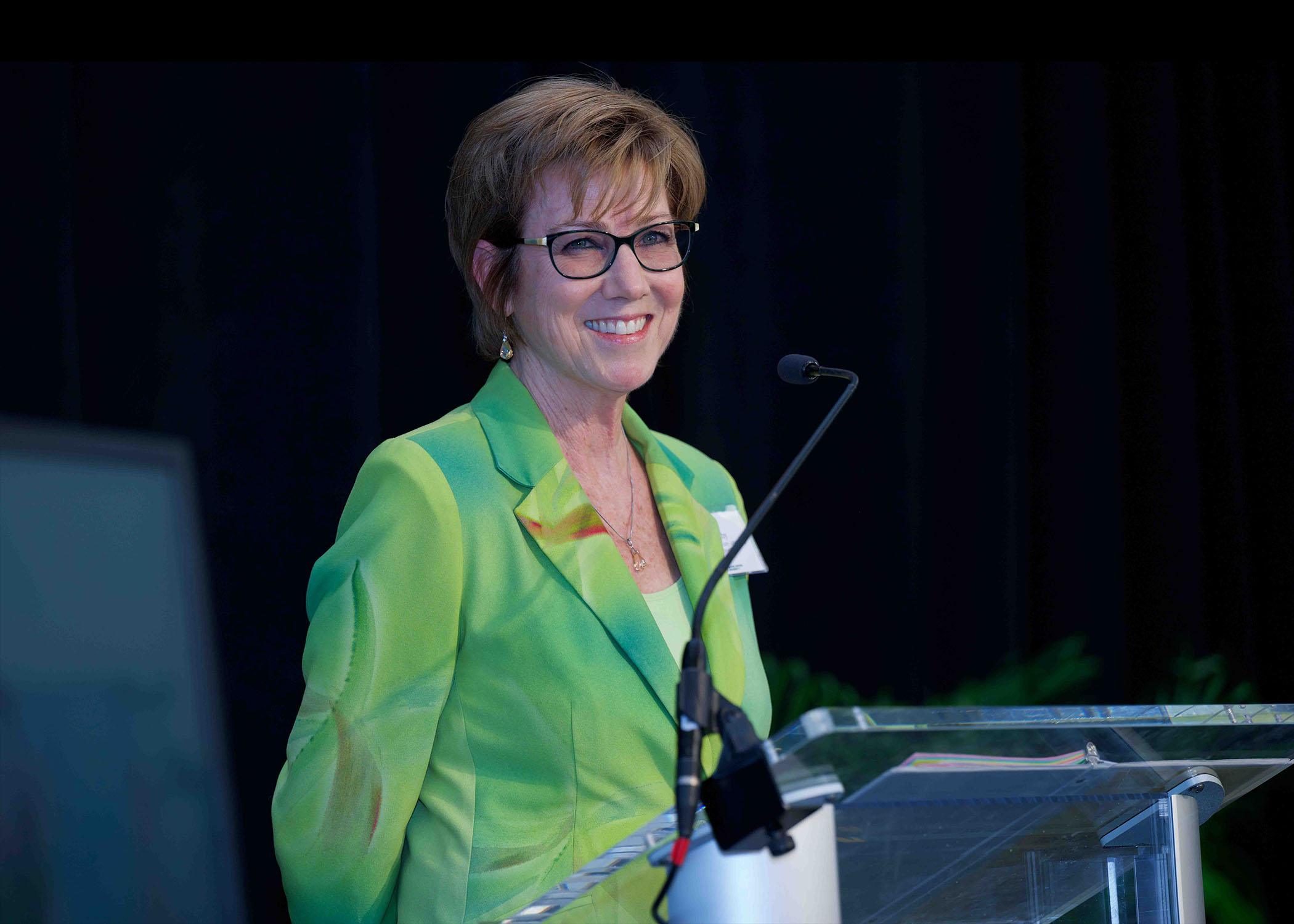 Kim Eby stands at podium at Celebrating Our Champions event.