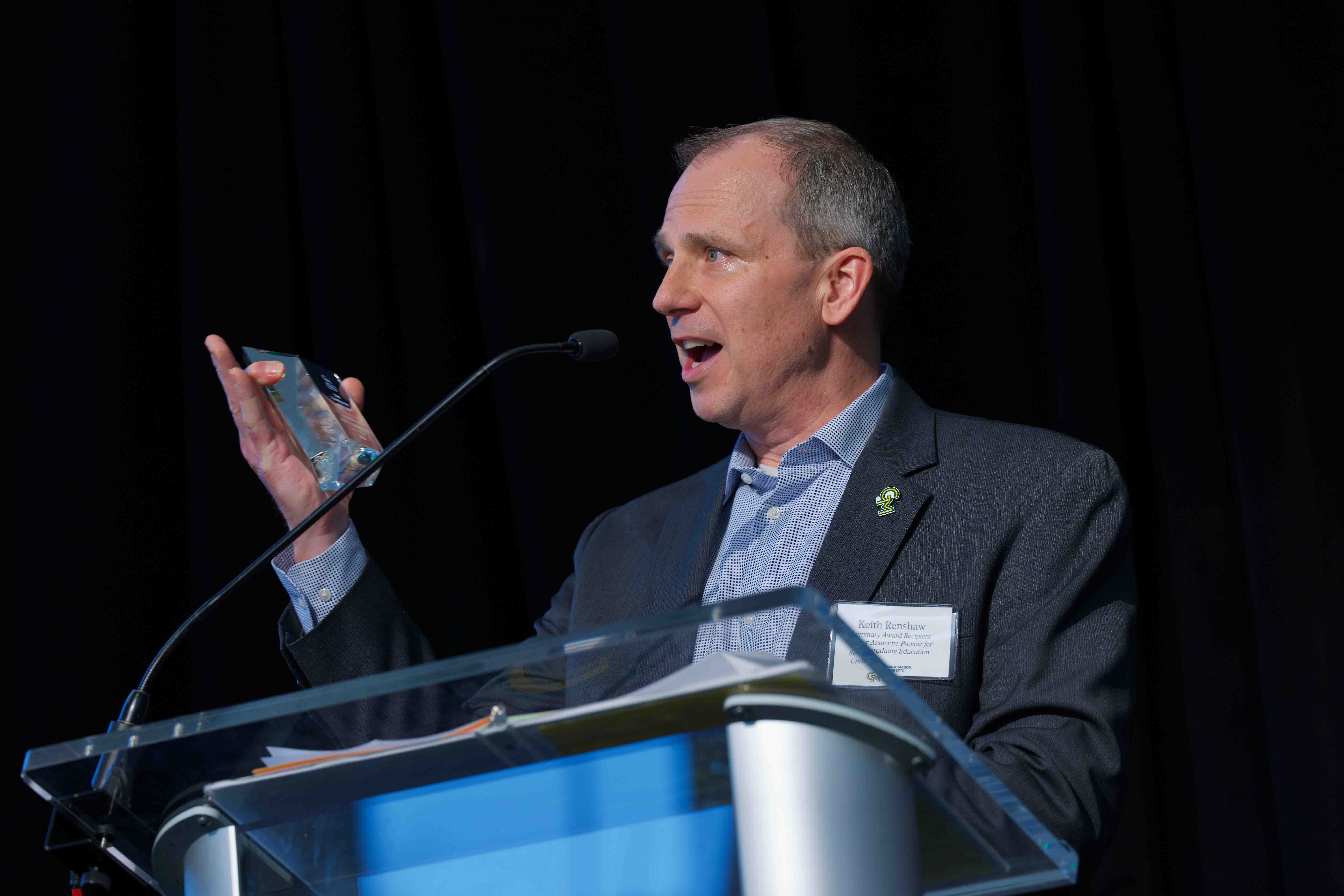 Keith Renshaw stands at podium at Celebrating Our Champions event.