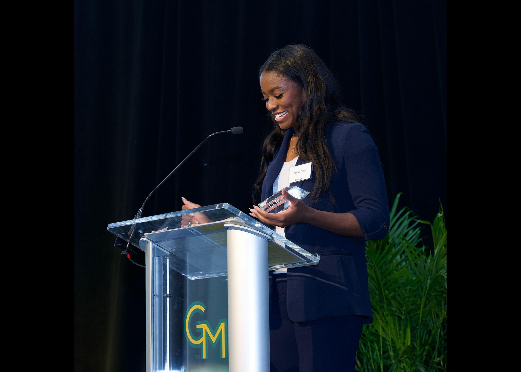 Chelsea Colter stands at podium at Celebrating Our Champions event.