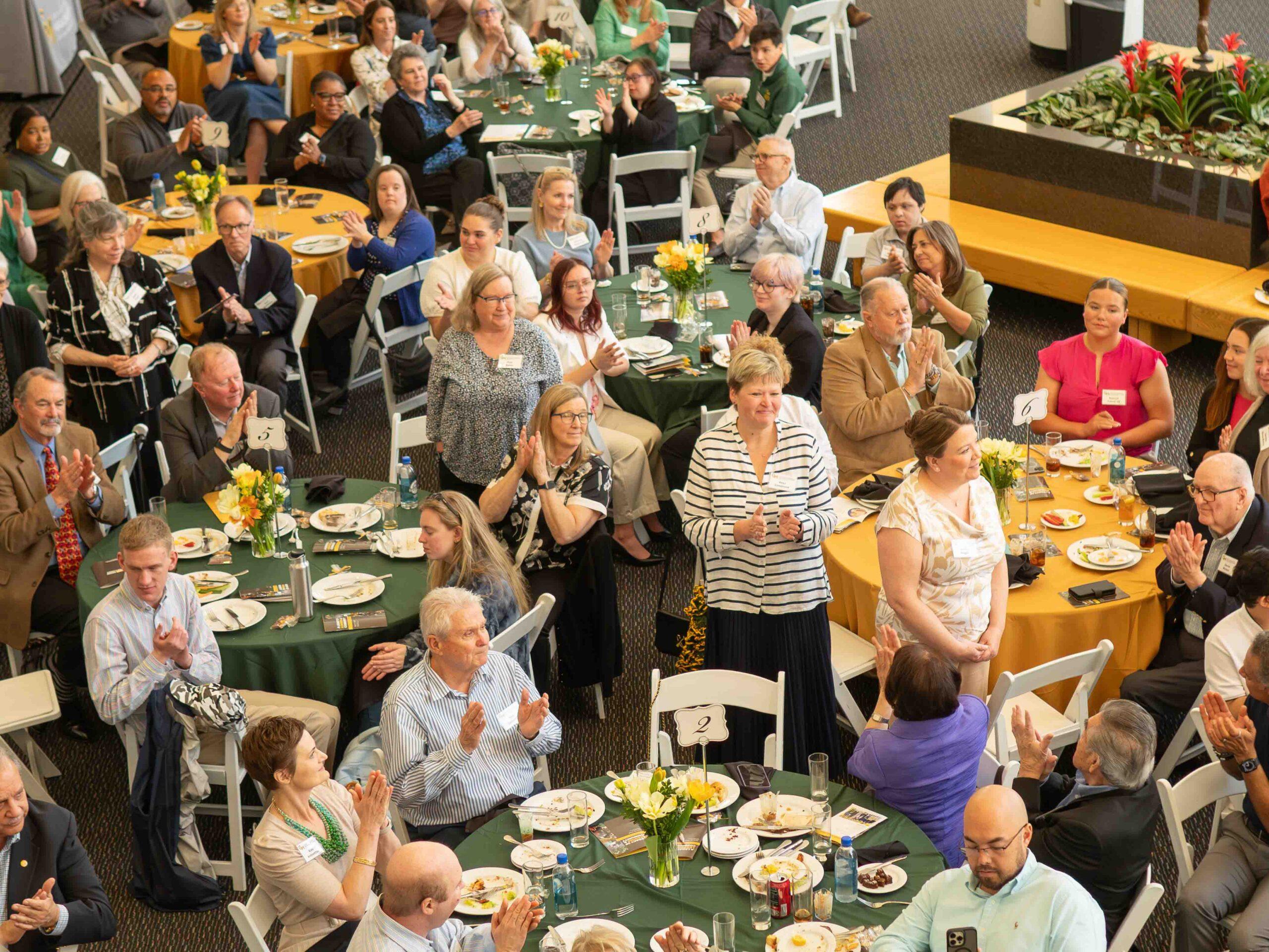 Mason LIFE 20th Anniversary guests seated at tables and applauding.