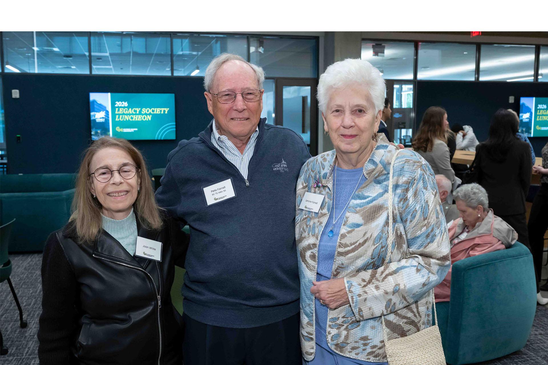 Three event attendees pose together in the reception space.