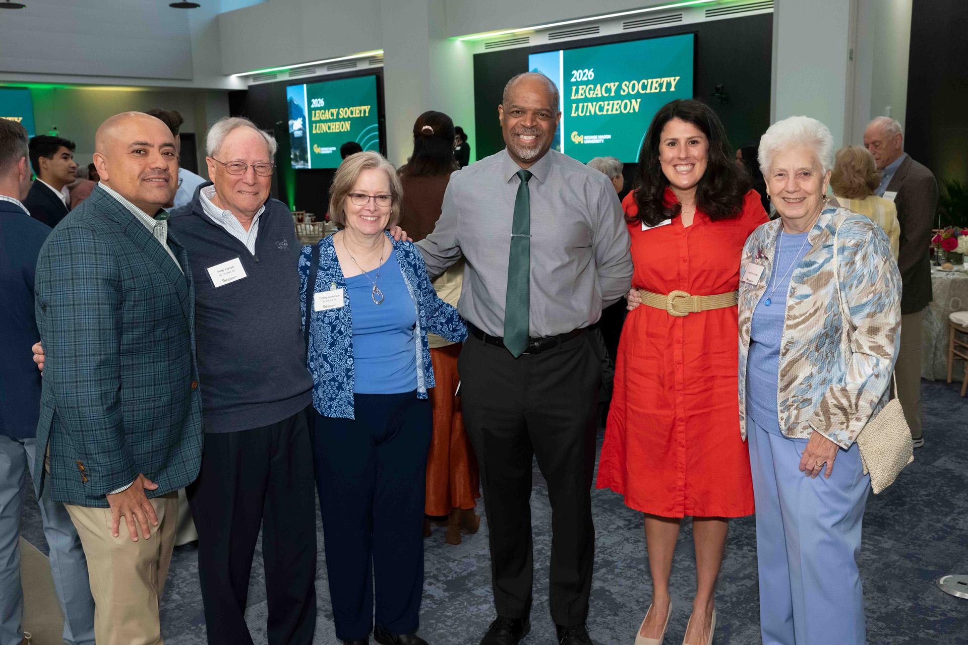 Six event attendees pose together in the reception space.
