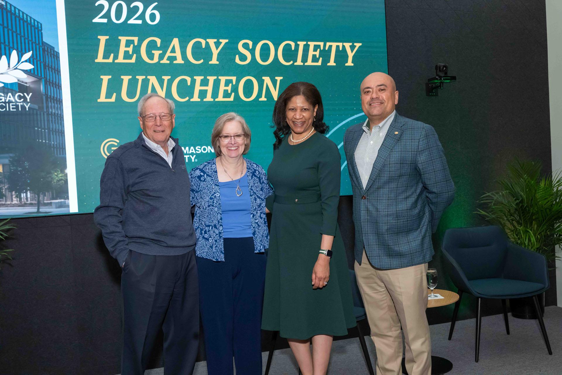 Two event attendees posed with two event speakers on stage.